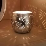 Metalen theelicht houder met perforaties, sfeervolle verlichting en schaduw effecten voor gezellige ambiance, ideaal voor woon- en slaapkamerdecoratie.