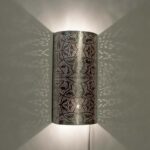 Decoratieve wandlamp met perforaties die sfeervolle lichtpatronen creëren, ideaal voor interieurdecoratie en ambiance.