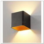 Wandlamp met zwart metalen behuizing en warm oranje binnenzijde, modern Design, sfeervolle laagstaande verlichting, zwart en oranje accenten, LED-verlichting, design lamp voor interieur, LICHY LAMPEN, elegante wandverlichting.