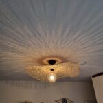 Unieke LICHY plafondlamp met houten rand en verlichting die een sfeervol licht en interessante schaduwpatronen op het plafond creëert. Perfect voor moderne en gezellige interieurinrichting.