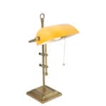 Vintage bureaulamp met goudkleurige metalen basis en oranje kap, ideale functionele verlichting voor kantoor of studeerkamer.