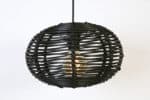 Donkergekleurde rieten hanglamp met vintage gloeilamp voor sfeerverlichting en decoratie.